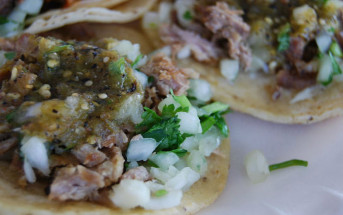 two carnitas tacos covered in salsa and toppings