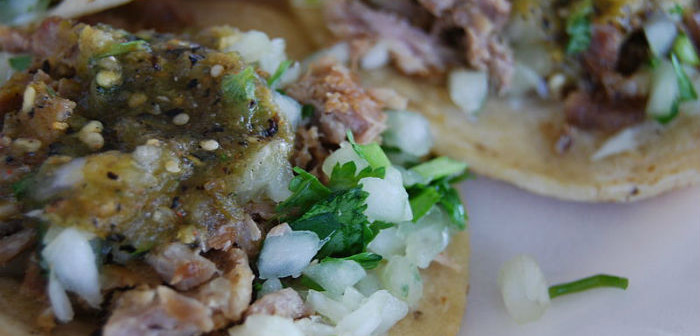 two carnitas tacos covered in salsa and toppings