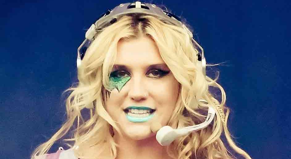 Pop artist Kesha decorated in glitter and dollar signs singing on stage (Kesha_2011_2.jpg: Peter Neillderivative work: Tabercil/Wikipedia Commons).