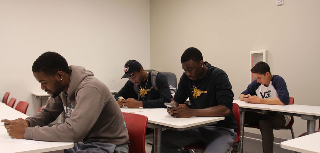 Saddleback College students engaging with their phones rather than with each other.